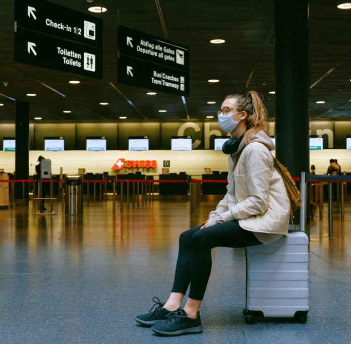 Woman sitting on a suitcase in an airport terminal