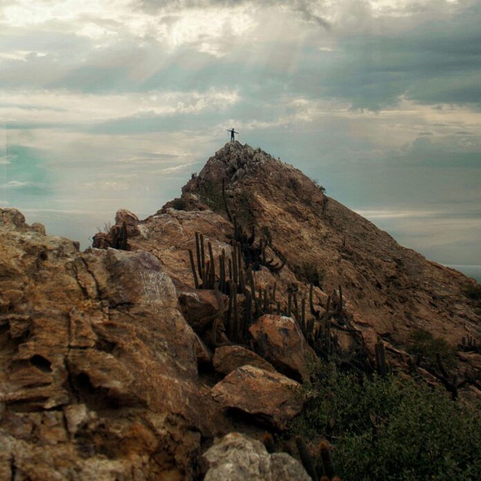 Cloudy landscape of a mountain with a person standing on top