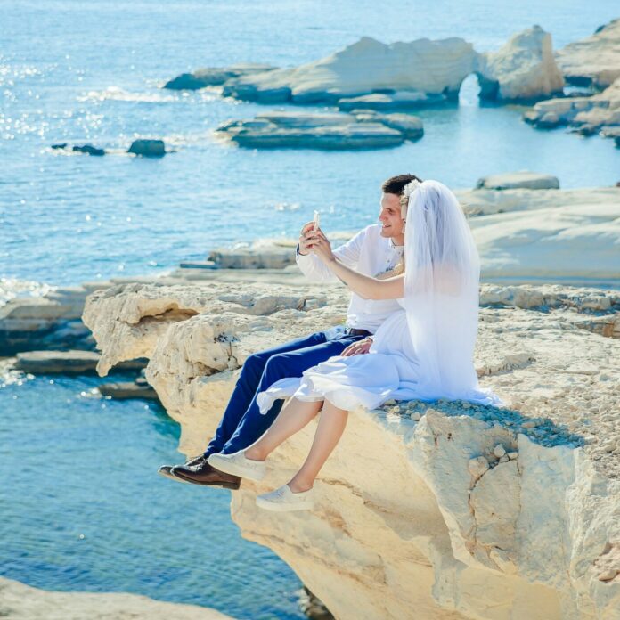 Newlywed couple sitting on a cliff
